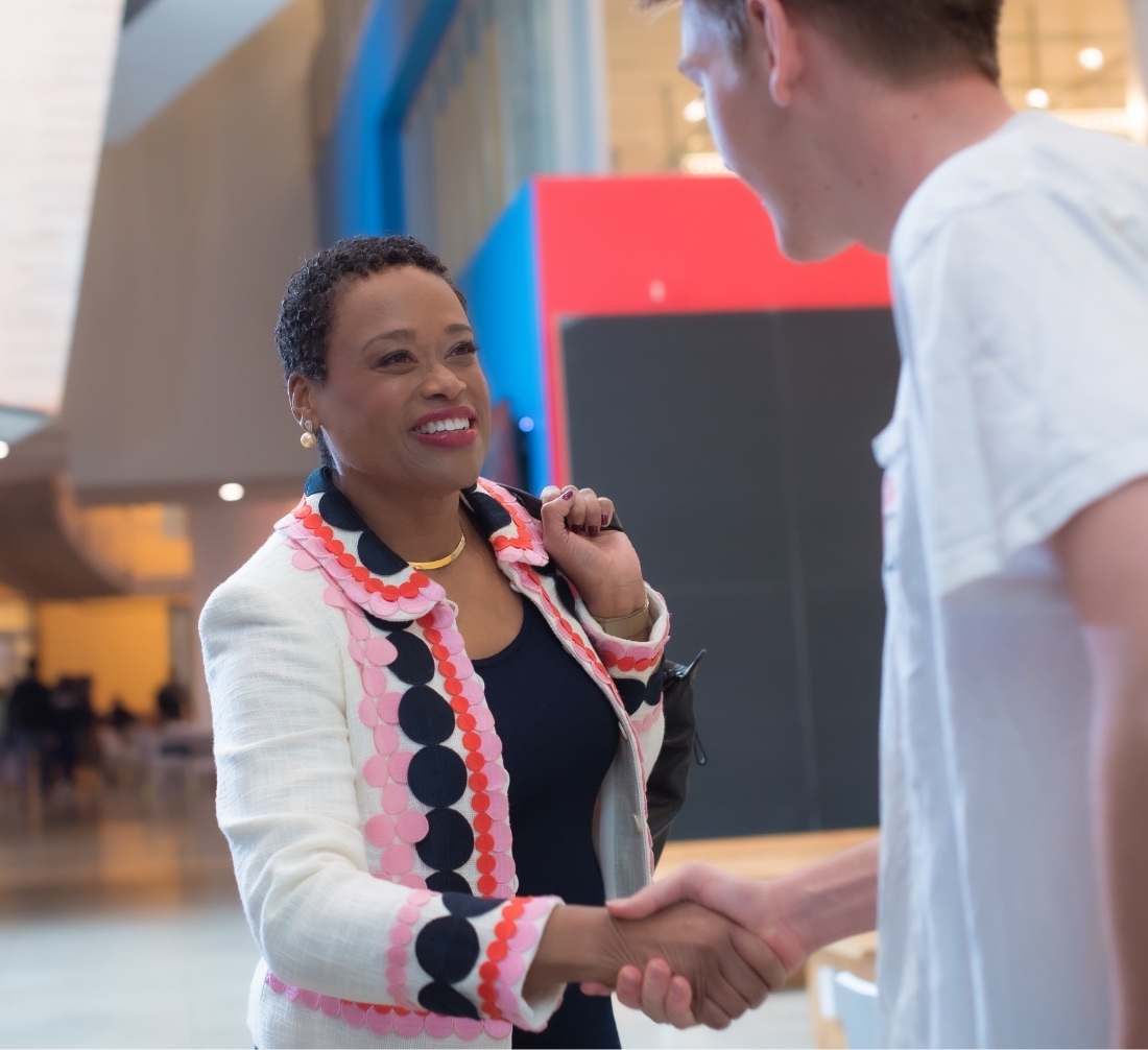 Chancellor Nobles smiles while shaking the hand of a student.