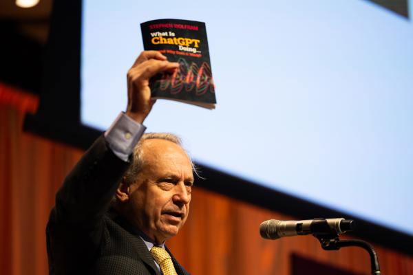 Rodney Brooks, iRobot co-founder and former director of CSAIL, holds up a copy of Stephen Wolfram's book, "What is ChatGPT Doing. . .and Why Does it Work," which he suggested attendees at the “Generative AI: Shaping the Future” Symposium read for background information on the technology.