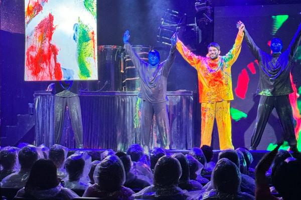 An enthusiastic audience participant from Course 5.111 (second from right) takes a bow with the Blue Men before an audience of fellow 5.111 students.